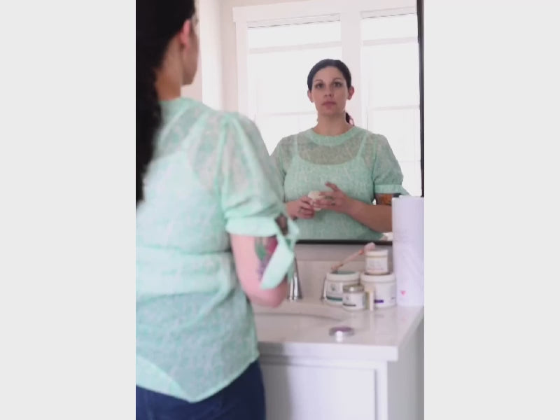 Woman applying Pure & Coco Flora Mango Butter Face & Body Crème to her face for soft, glowing skin.