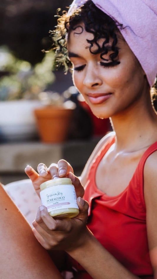 Woman holding a jar of Capri 5-in-1 Sugar Scrub wearing a bathing suit