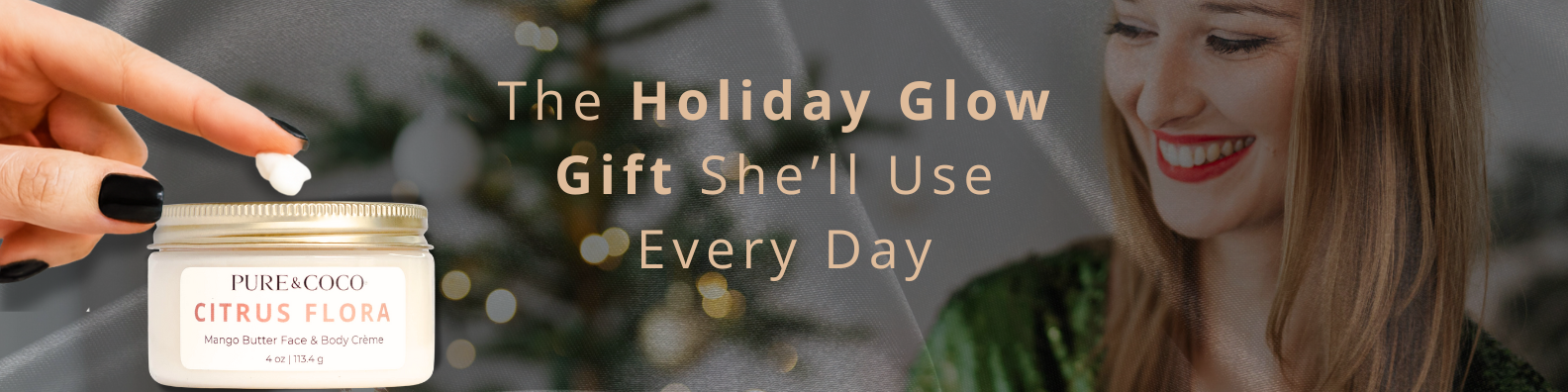 Woman smiling near Christmas tree while applying Pure & Coco Citrus Flora Mango Butter Face & Body Crème – a luxurious holiday skincare gift for glowing, hydrated skin.