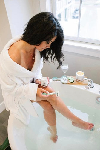 woman shaving her legs with the organic coconut oil face and body polish_pure and coco